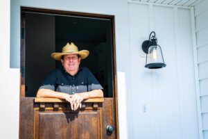 A Man in a Cowboy Hat by a Stable Door